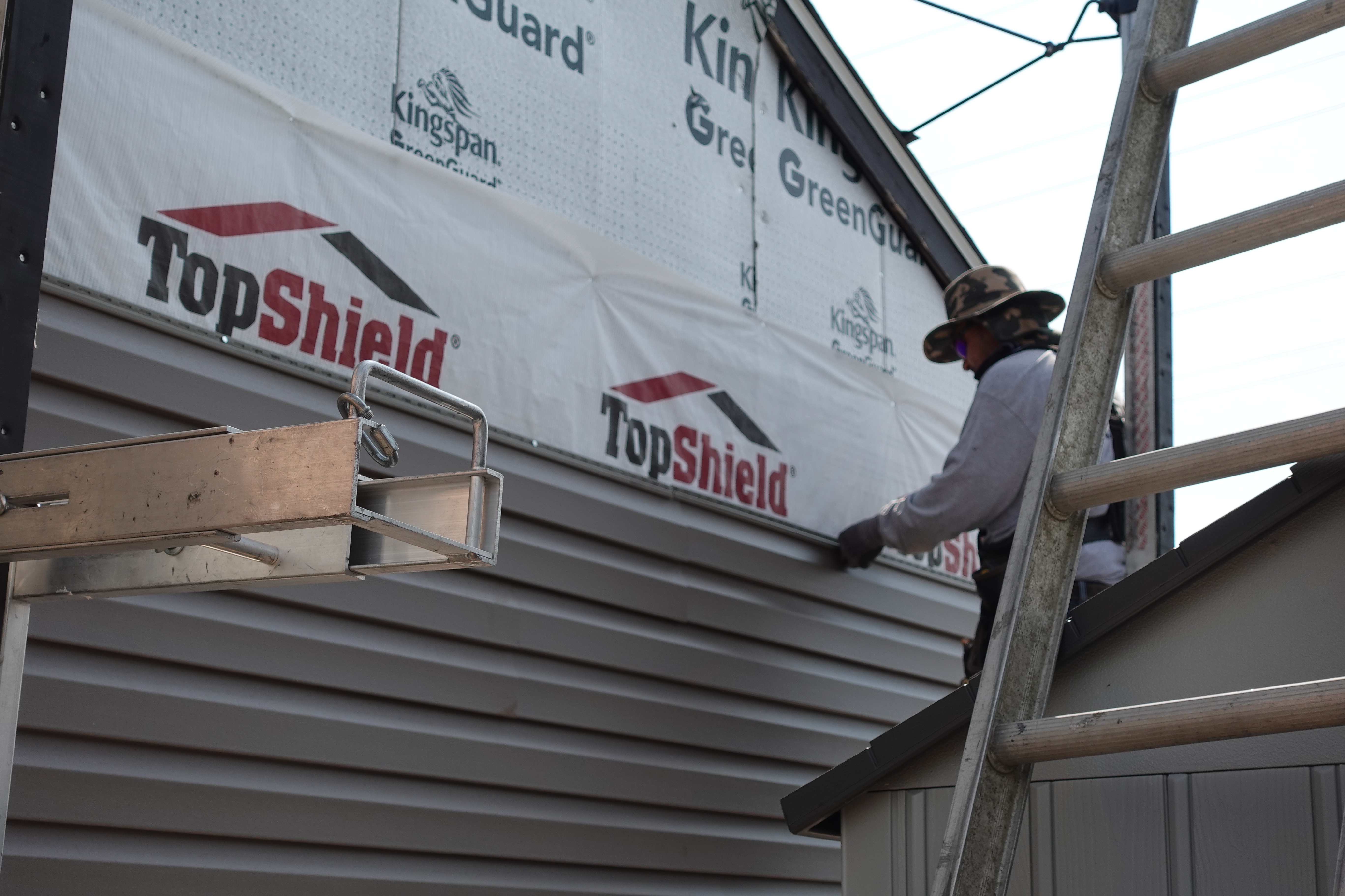close up of person drilling siding on a house